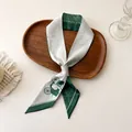 Gros plan d'un foulard twilly en satin vert avec motif de calèche sur plateau bois - 100PD-093 / 7*100cm