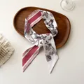 Détail d'un foulard en soie twilly avec imprimé fleuri et papillon sur un plateau décoratif - 100PD-094 / 7*100cm