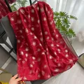 Detail of red floral scarf with golden dandelion print and beaded tassels on a chair - Red