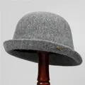 Dettaglio cappello cloche in feltro di lana grigio scuro con emblema piuma dorata - M / Grigio chiaro