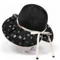 Detail of sun hat showing spiral weave texture, letter print brim, and gold metal buckle - M (56-58cm) / Black