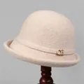 Detail eines beigen Wollfilzhutes mit goldenem CH-Metalllogo und elegantem Zierband - M (56-58cm) / Beige