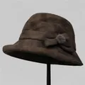 Detail van donkerbruine wollen cloche hoed met strik en pluizige bont pom-pom decor - M / koffiekleur