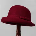 Close-up of deep red wool felt cloche hat with rolled edge and bow detail on wooden stand - M (56-58cm) / Burgundy