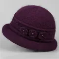 Close-up of deep purple knit winter hat with plush fur texture and floral decorations - Purple