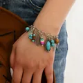 Dettaglio del bracciale boho vintage con pietre turchesi e ciondoli sul polso - Stile Foglia