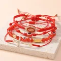 Dettaglio del set di 4 braccialetti rossi intrecciati con perline, malocchio e croce - Rosso