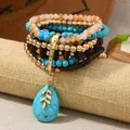 Dettaglio set bracciali bohémien con perline turchesi, legno e ciondolo a foglia dorata - Multicolore