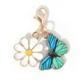 Gouden sleutelhanger met wit madeliefje en blauw-groene geëmailleerde vlinder hanger - Blauwe Vlinder Witte Bloem