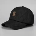 Detail der schwarzen gesteppten Wintermütze mit Ohrenschutz und Leder-Logoaufnäher - Verstellbar / Schwarz