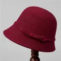Close-up of wine red wool cloche hat featuring an elegant bow on a classic wooden stand - M (56-58cm) / Burgundy