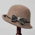 Detail of wool felt cloche hat with rhinestone bow on a wooden stand - M (56-58cm) / Camel
