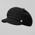 Detalle de gorra de lana negra con textura de tela y un botón decorativo de metal plateado - M / Negro