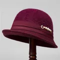 Detail of burgundy knit cloche hat with satin ribbon and pearl accent on wooden stand - M (56-58cm) / Burgundy