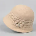 Detail of beige knitted winter hat with intricate floral pattern and silver buckle accent - M / Beige
