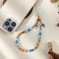 Detail of wooden beads and blue resin charms on a woven phone strap with golden metal clasp - Blue Resin Bead And Wood Bead Style (ML467)