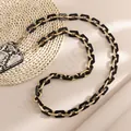 Detail van de acryl telefoonkabel met gouden ringen en slangenprint textuur - Zwart