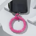 Handmade pink beaded phone wrist strap with metal spring clasp on minimalist background - Watermelon red