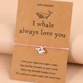 Bracelet de vœux tressé rose avec pendentif baleine argenté sur carte cadeau en kraft - Baleine-Rose