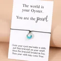 Handgewebtes Armband mit blauem Muschelanhänger und Perle auf Geschenkkarte - Seeblau