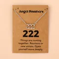Vue macro du pendentif chiffre ange 222 argenté sur une carte cadeau kraft marron - 222