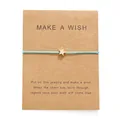 Dettaglio del braccialetto dei desideri blu con stella in oro rosa su carta kraft - Verde