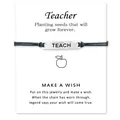 Detail des TEACH-Anhängers auf schwarzem Armband mit einer Grußkarte für Lehrer - Grau