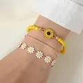 Dreiteiliges Gänseblümchen-Armband-Set mit Sonnenblumen-Anhänger am Handgelenk des Models - Gänseblümchen - Armband
