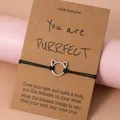 Handgemaakte zwarte gevlochten wensarmband met zilveren kattenoor bedel op een kaart - Opengewerkte Kat Armband