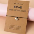 Bracelet cordon noir fait main avec breloque dinosaure argentée sur carte de vœux - T-Rex