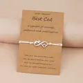 White woven rope bracelet with cat infinity heart charm on a brown gift card - White