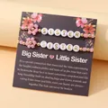 Bracelets bohèmes en perles roses avec fleurs de chance et lettrage Sister sur carte - Ensemble 2 pièces SISTER-1 avec carte