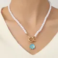 Bohemian pearl bracelet with daisy charm and golden toggle clasp on model wrist - Clavicle Necklace Blue Daisy Pearl Style (Necklace Blue)