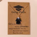Golden graduation gown pendant necklace on a kraft gift card with black and blue enamel detail - Academic Gown Style 2