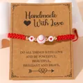 Handgemaakte rode gevlochten honkbal armband met hartjeskralen op een displaykaart - Rood Touw / Honkbal