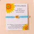 Light blue woven bracelet with yellow sunflower charm on a decorative card - Sky Blue
