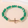 Elastische kralenarmband met groene kristallen kralen en gouden kruis hanger - Groen