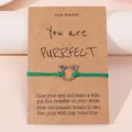 Groene geweven kattenarmband met zilveren kattenoor-bedel op een displaykaart - Groen