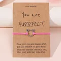 Roze geweven wensarmband met zilveren kattenbedeltje op een cadeaukaartje - Roze