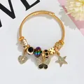 Golden twisted wire bangle with heart, butterfly, and star charms in bohemian style - Black