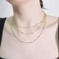Three-layer gold snake chain necklace with metallic beads shown on a model - Gold