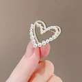 Broche cœur doré ornée de perles blanches et cristaux, présentée sur les doigts - Coeur Perle