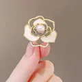 Élégante broche camélia dorée avec pétales en nacre blanche et détail de perle centrale - Camélia