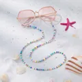 Detail einer bunten Boho Brillenkette mit LOVE-Perlen auf einem sonnigen Strandhintergrund - Weiß Bunt Love