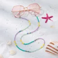 Detailansicht der bunten Brillenlkette mit Herzperlen auf sommerlichem Sandhintergrund - Farbblock-Herz