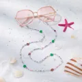 Roze oversized zonnebril met kleurrijke bloemen kralenketting op wit strandzand - Kleurrijke bloem