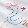 Brillenkette mit blauen Glasperlen, LOVE-Buchstaben und Seesternen auf Sand - Irisierender Blauer Stern