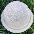Elegant white knitted round-top sun hat with rolled brim shown in natural outdoor setting - Cream