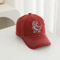 Close-up of red kids baseball cap with dinosaur embroidery and white contrast stitching - Adjustable / Red