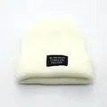Minimalist beige ribbed knit beanie featuring a black slogan patch for winter warmth - Adjustable / White